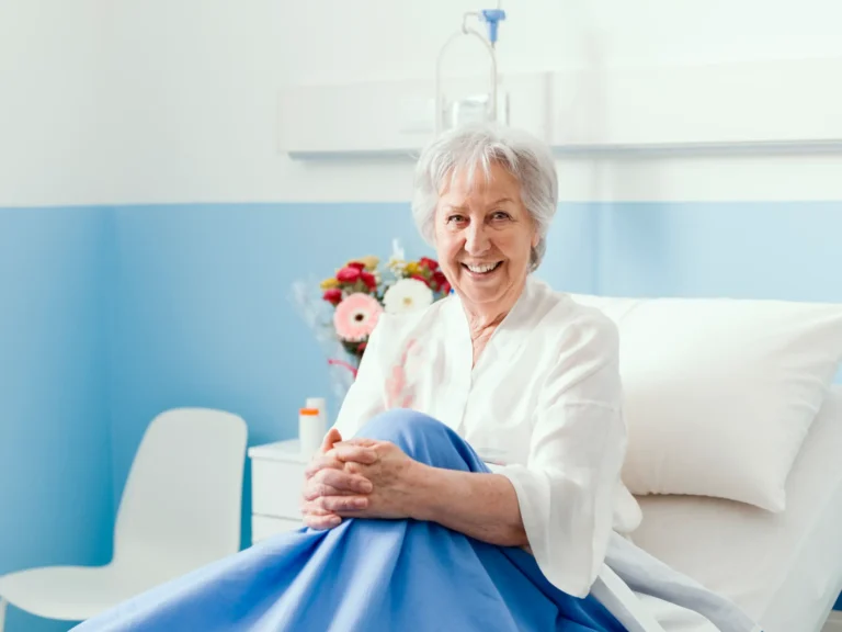Smiling senior woman in a comfortable bed, receiving supportive catheter care in Truro or Swindon.