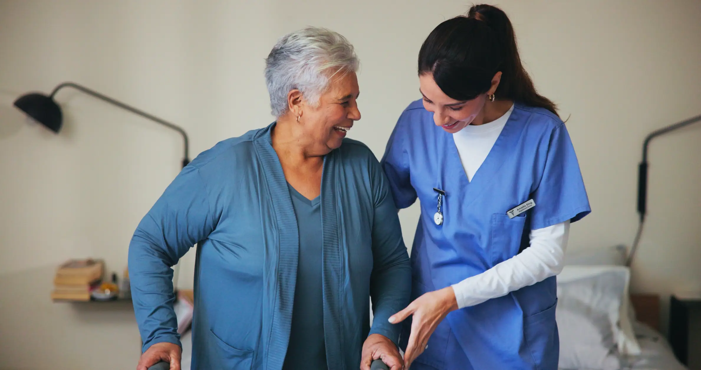 Home healthcare nurse assisting an elderly woman with gentle support down stairs.