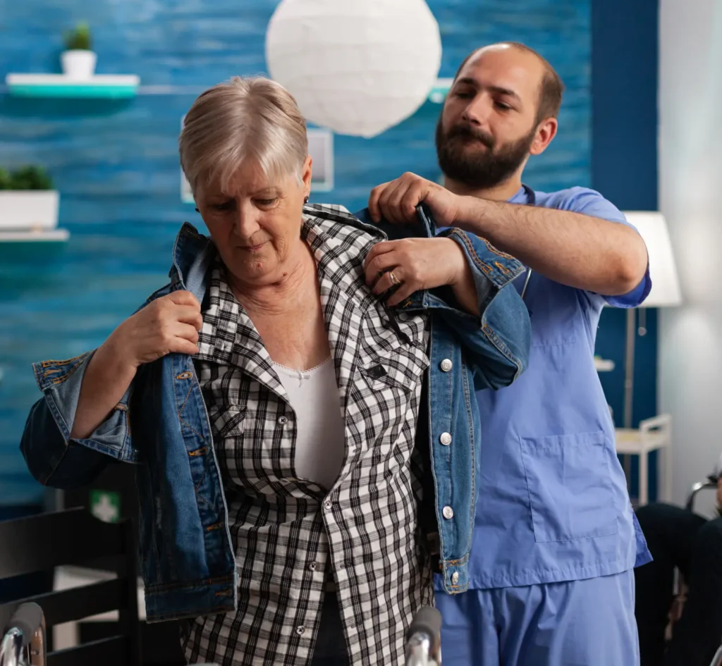 Carer helping a senior woman with dressing as part of in-home personal care in Truro and Swindon.
