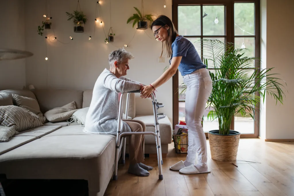 Professional live-in carer in Swindon and Truro helping a senior woman with a walker in a brightly lit home environment, ensuring safe mobility.