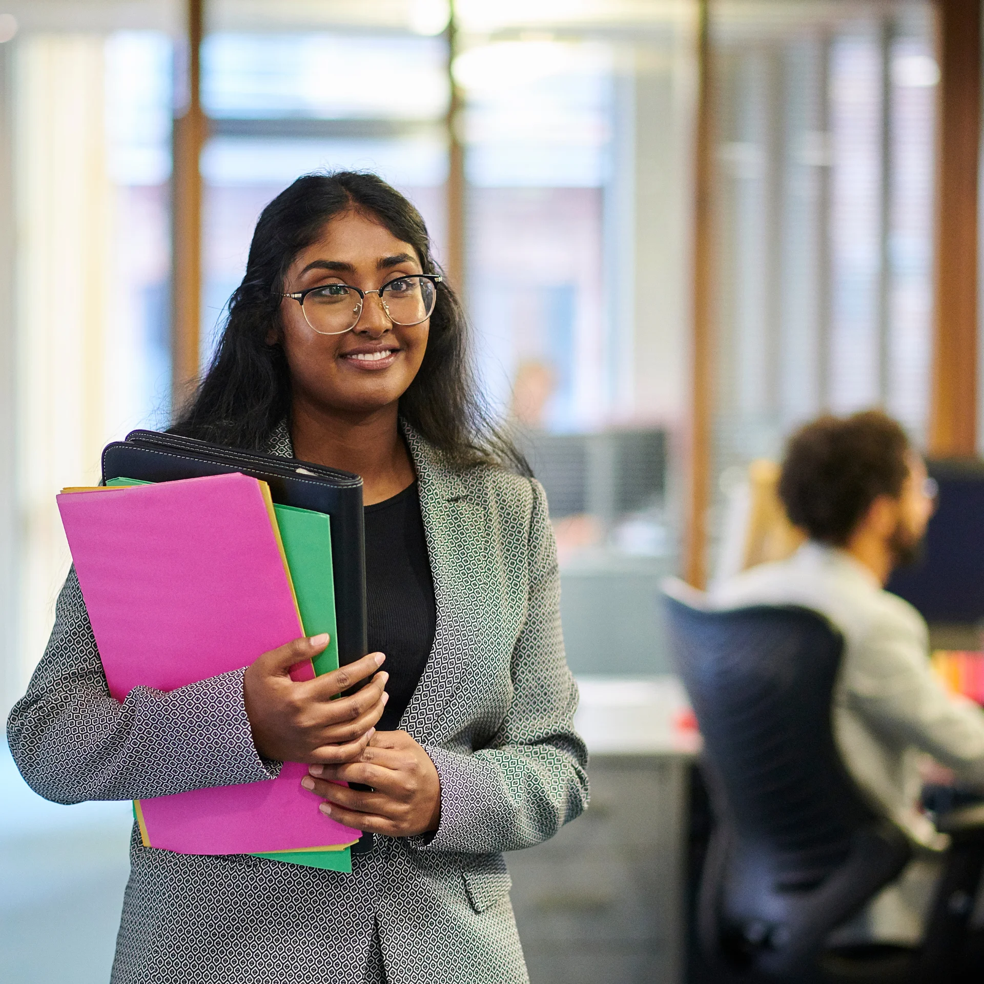 Female professional in an office holding files, representing local care partnerships.