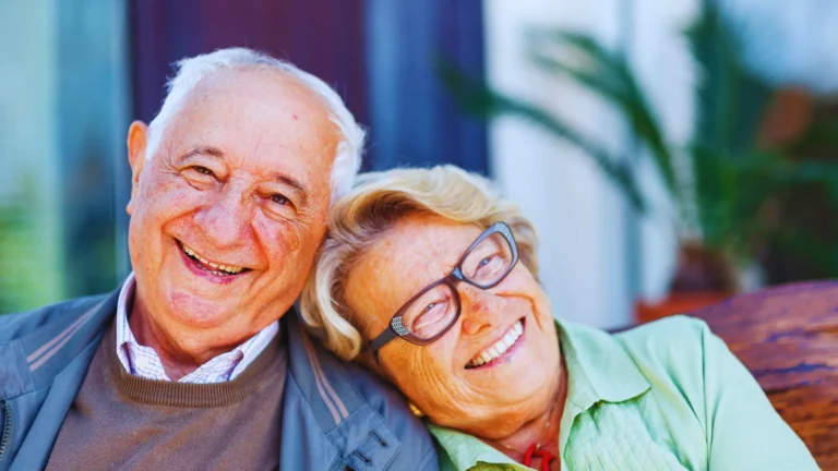 Elderly couple smiling and leaning on each other with warmth and trust