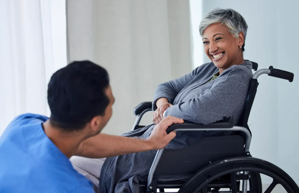 Compassionate carer assisting smiling wheelchair user with mobility support in Truro & Swindon
