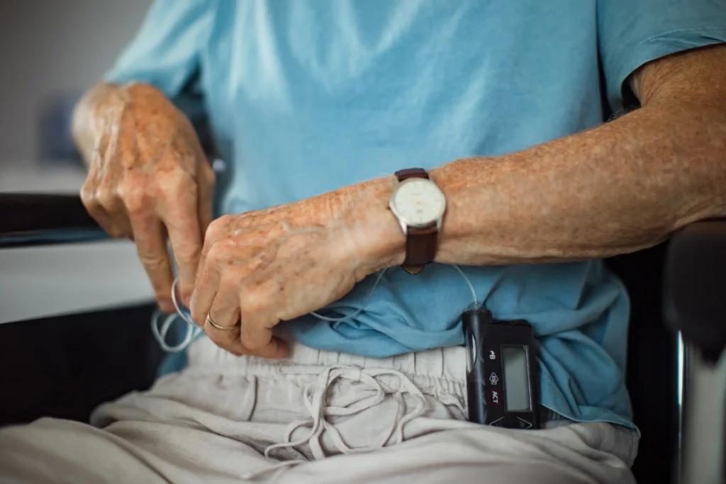 Senior man managing a medical device, symbolizing professional catheter care management at home in Truro and Swindon.