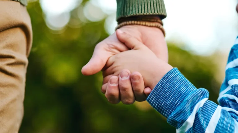Adult and child holding hands, symbolising support and trust for children with special needs.