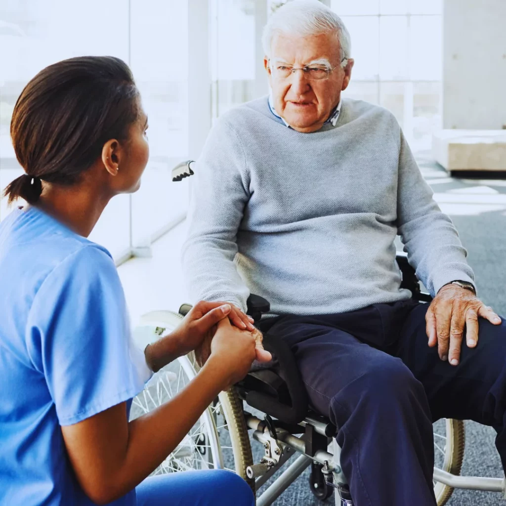 Bristol home carer sitting with an older man in a wheelchair, offering support